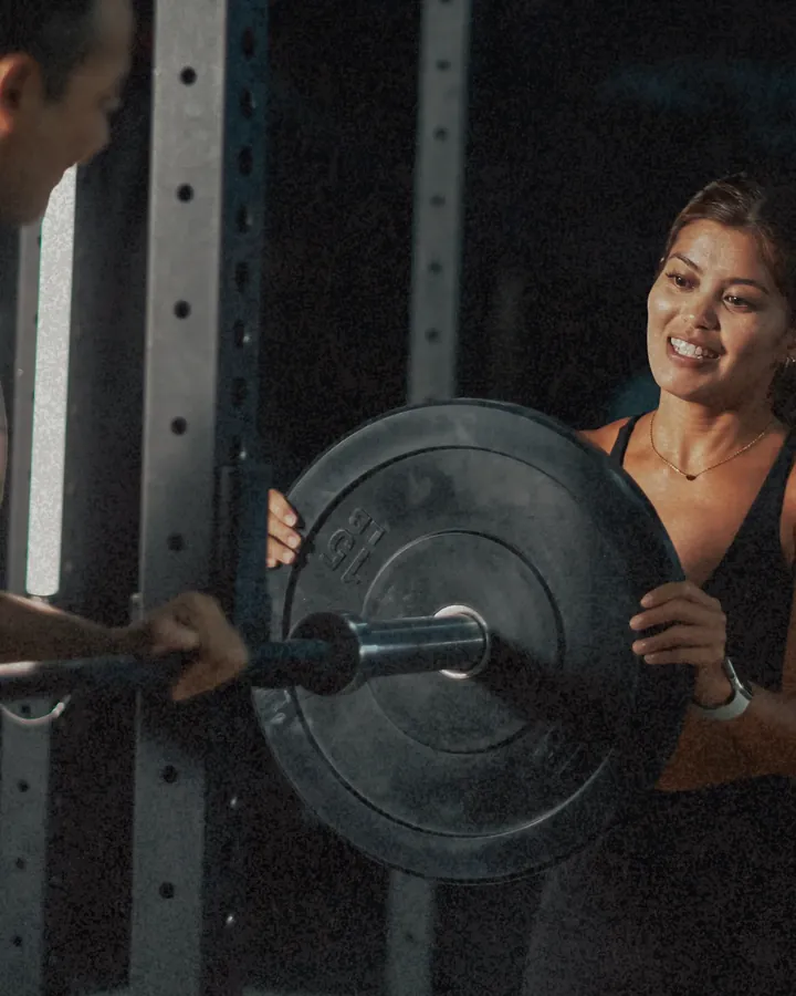 A coach providing one-on-one instruction to a new member in a gym setting.